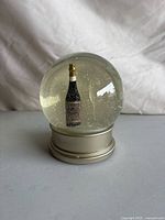 Front view of snow globe showing champagne bottle figurine