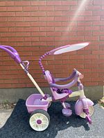 Side view of convertible purple kids tricycle with sun shade attached