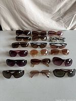 All fifteen pairs of sunglasses arranged in rows on table