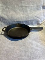 Angled view of Lodge 10-inch skillet showing interior, helper handle and silicone grip