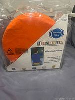 Front view of sealed Senseez orange vibrating pillow in packaging