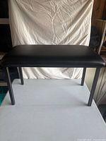 Front angled view of black upholstered bench on table