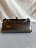 Front view of gunmetal metal purse showing curved handle and kiss-lock clasp