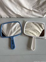 Blue and white handheld mirrors side by side