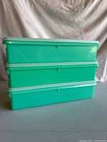 Stacked view of three jadeite green Tupperware containers with white lids
