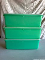 Three stacked jadeite green Tupperware containers with lids on