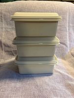 Stacked view of three lidded Tupperware containers showing color and shape