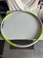Full view of assembled grey and green weighted hula hoop on table