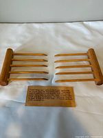 Full view of both wooden tongs and care plaque on white surface