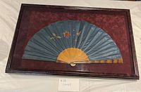 Front view of framed shadow box showing silk fan and mat