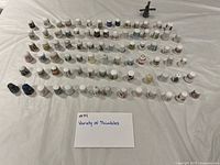 Overhead view of rows of approximately 80 assorted sewing thimbles on table