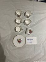 Set laid out showing six cups and one saucer with floral motif and gold rims