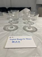 Front view showing four of the six clear crystal coupe glasses on table.