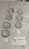 All seven crystal snifter glasses in two rows, plain set on left and etched set on right, labelled 4 and 3