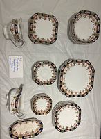 Full set laid out showing gravy boat, underplate, stacks of plates and bowls in Imari pattern