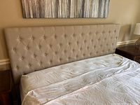 Full view of beige upholstered king headboard attached to bed base
