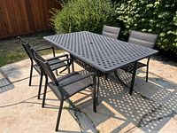 Full view of rectangular cast aluminum patio dining table with four matching chairs