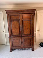 Front view of Drexel Heritage armoire showing two upper and two lower paneled doors, metal base apron