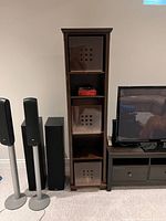 Full view of shelving unit with three bins inserted, next to other furniture for scale