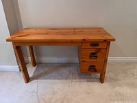 front view of wooden desk showing three drawers, legs, top