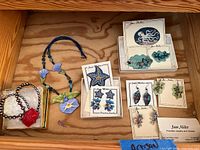 Drawer view of all jewelry pieces arranged, showing necklaces, bracelets and boxed porcelain items