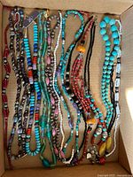 Top view of all thirteen beaded necklaces in box