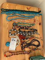 All fifteen necklaces laid out on wooden surface