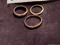 Three gold bands on dark fabric background