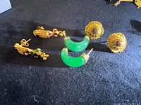 Three pairs earrings laid out: filigree studs, drop earrings, green crescent hoops