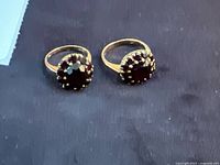 Two gold cluster rings side by side on black surface