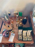 Overview of tabletop showing full assortment of perfume and cologne bottles, three green presentation boxes and decorative gift box