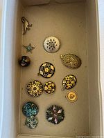 All twelve pins and pendants arranged in box