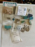 All items together displayed: earrings, ring, pendants, necklace, business card