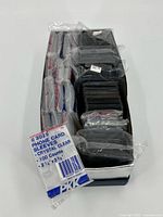 Open box showing sealed packs of sleeves and bundled top loaders