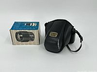 Camera case beside boxed Tokina lens