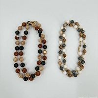 Two beaded necklaces laid flat showing bead colours and clasps