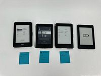 Group shot of four Kindle e-readers with sticky notes indicating generation and capacity