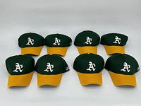Eight identical Oakland Athletics caps arranged in two rows