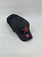 Stack of identical black Houston Astros caps front view showing embroidered logo and size sticker