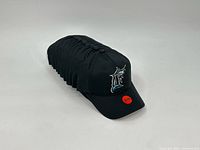Stack of twelve identical black Florida Marlins caps front view