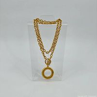 Full view of gold-tone chain with magnifier pendant displayed on stand