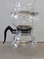 Straight-globe glass vacuum coffee maker showing handle, collar, upper and lower bowls
