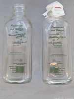 Front view showing both clear glass bottles with green Hewitt's Dairy text