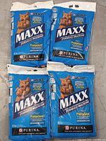 Four sealed 10 kg bags Purina MAXX cat litter on floor