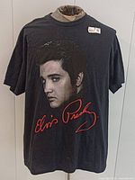 Full front view of T-shirt on mannequin showing portrait graphic and signature