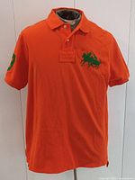 Front view of orange polo shirt on mannequin