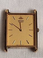 Front view of Seiko rectangular gold-tone watch head, showing dial and hands