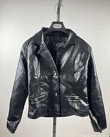 Full front view of black jacket on hanger