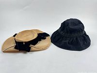 Straw hat and black bucket hat side by side, showing overall form and materials