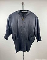 Front view of black SUPERFINE silk top on hanger showing zipper, pockets, cuffs, hem